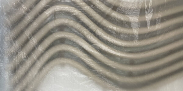 Abstract beeld van een beige en zwart patroon van golvende lijnen op een witte plastic achtergrond. 

Abstract image of a beige and black pattern of wavy lines on a white plastic background.